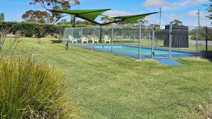 Zona exterior amurallada con piscina, estructuras sombreadas verdes y un cartel que indica 'Área de piscina'.