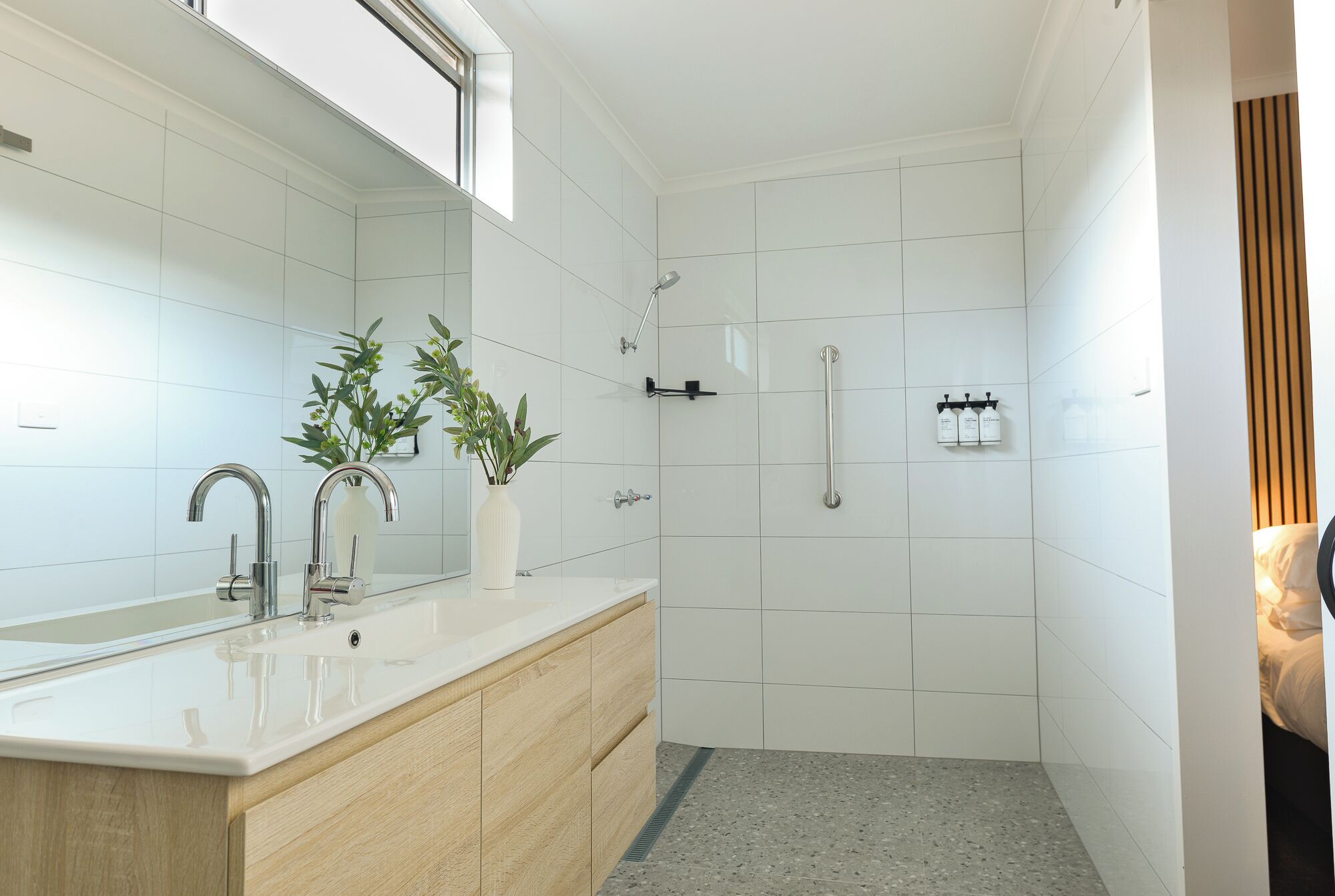 A modern bathroom with a large mirror, a sink, and a shower area.
