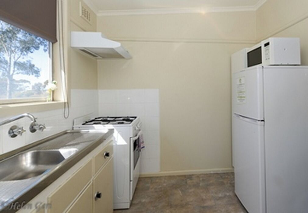 Cocina compacta con lavamanos, estufa y refrigerador.