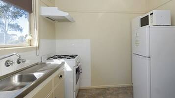 Cocina compacta con lavamanos, estufa y refrigerador.