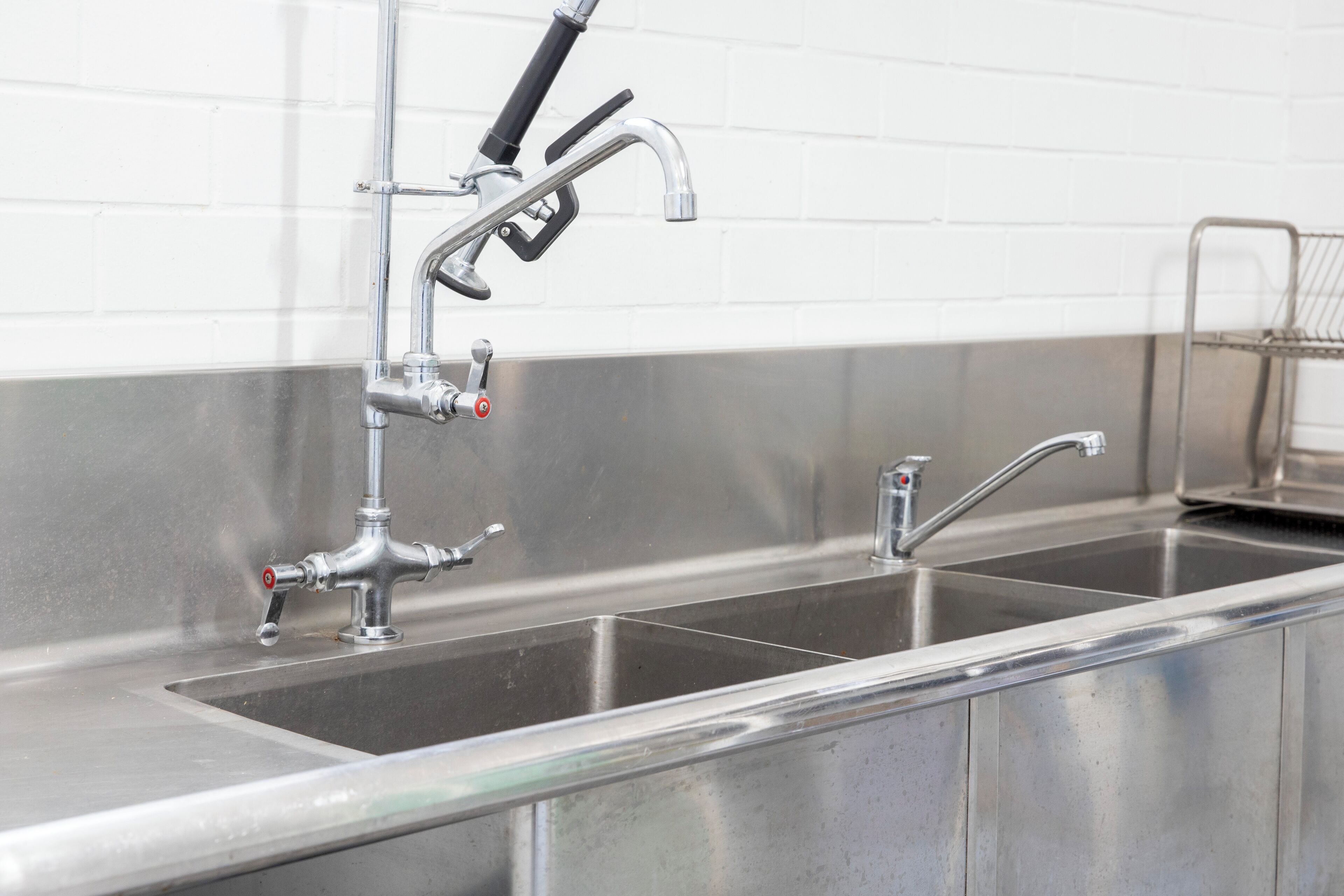A stainless steel kitchen sink with a faucet and a soap dispenser.