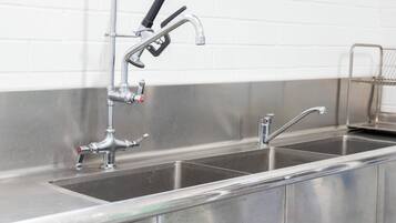 A stainless steel kitchen sink with a faucet and a soap dispenser.