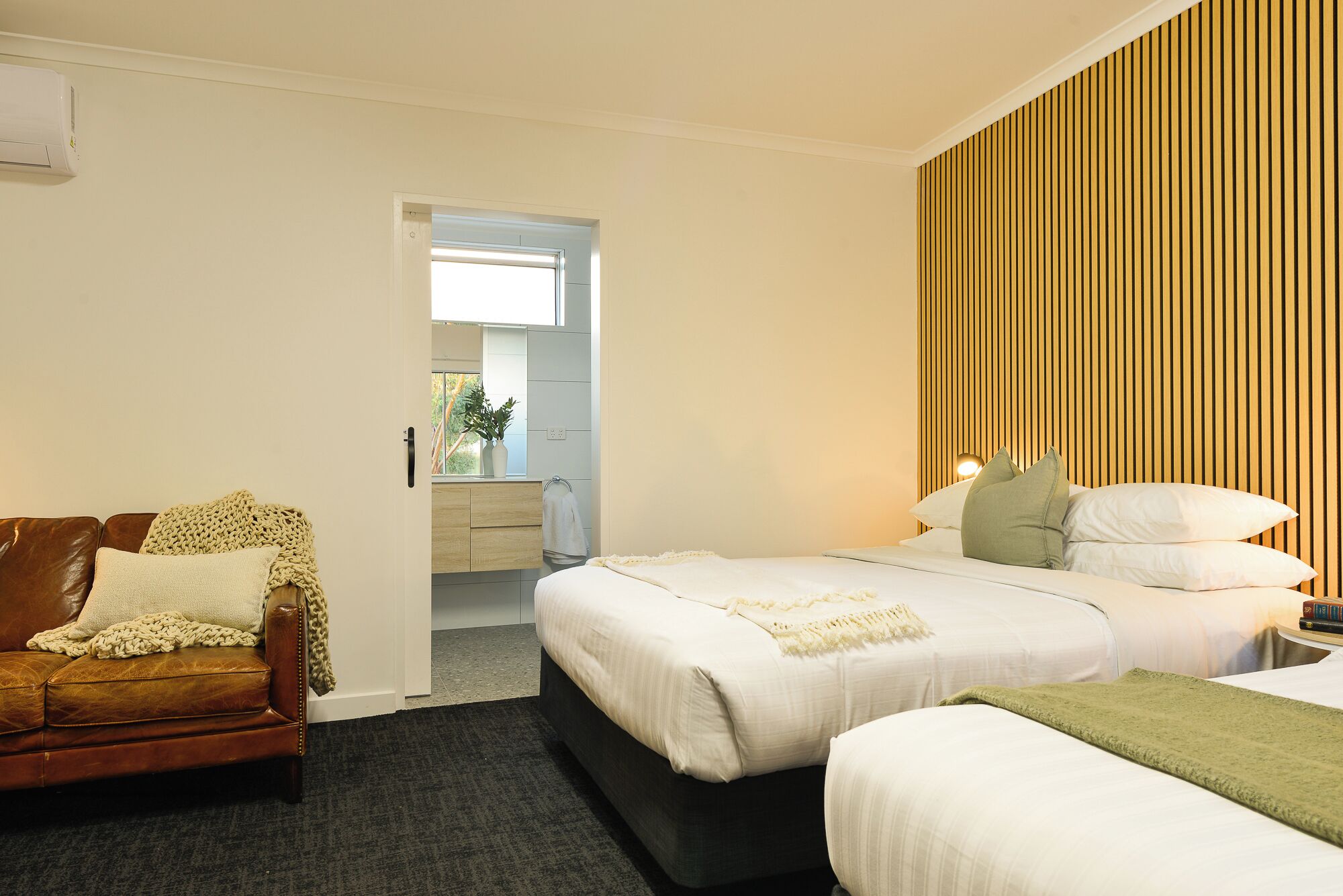 A hotel room with a bed, a sofa, and a small table with a lamp.