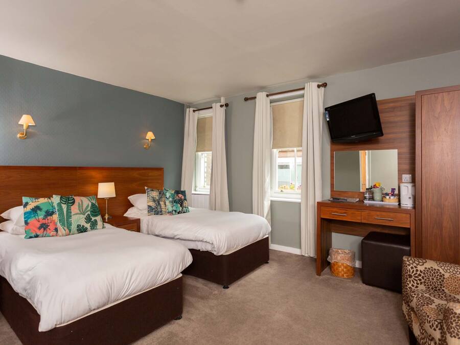 A hotel room with two beds, a desk, a television, and a wardrobe.