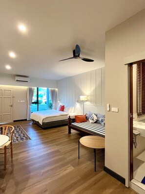 Une chambre d’hôtel avec un lit, un canapé, une petite table et un ventilateur de plafond.