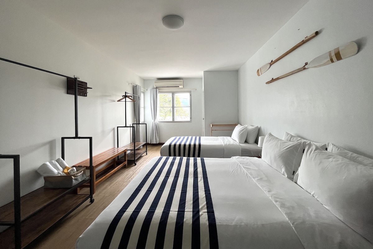 Una habitación de hotel moderna con una cama grande, una mesita de noche, un armario y una ventana con cortinas.