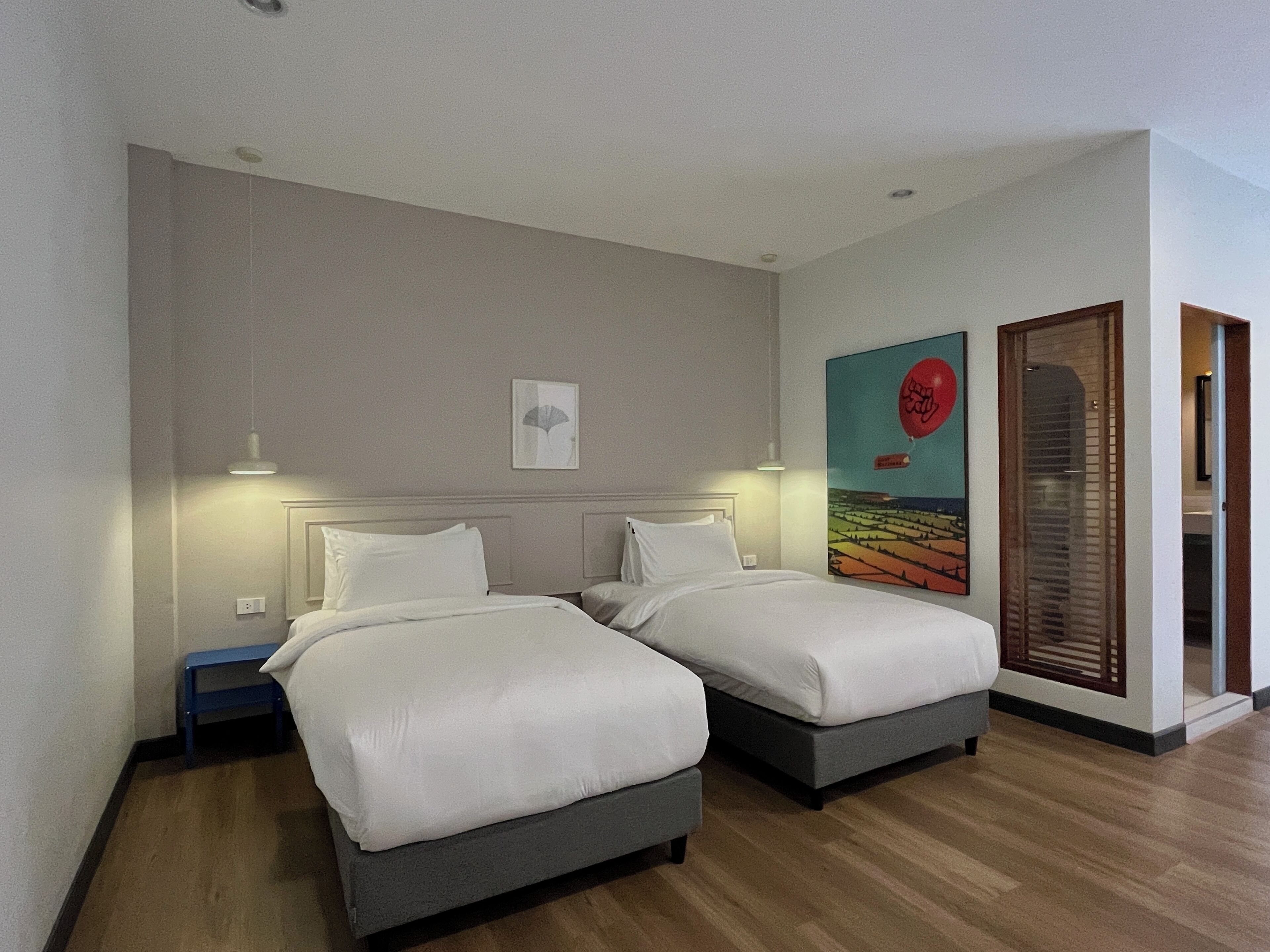 Una habitación de hotel con dos camas, una mesita y un cuadro en la pared.