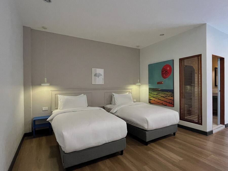 Una habitación de hotel con dos camas, una mesita y un cuadro en la pared.