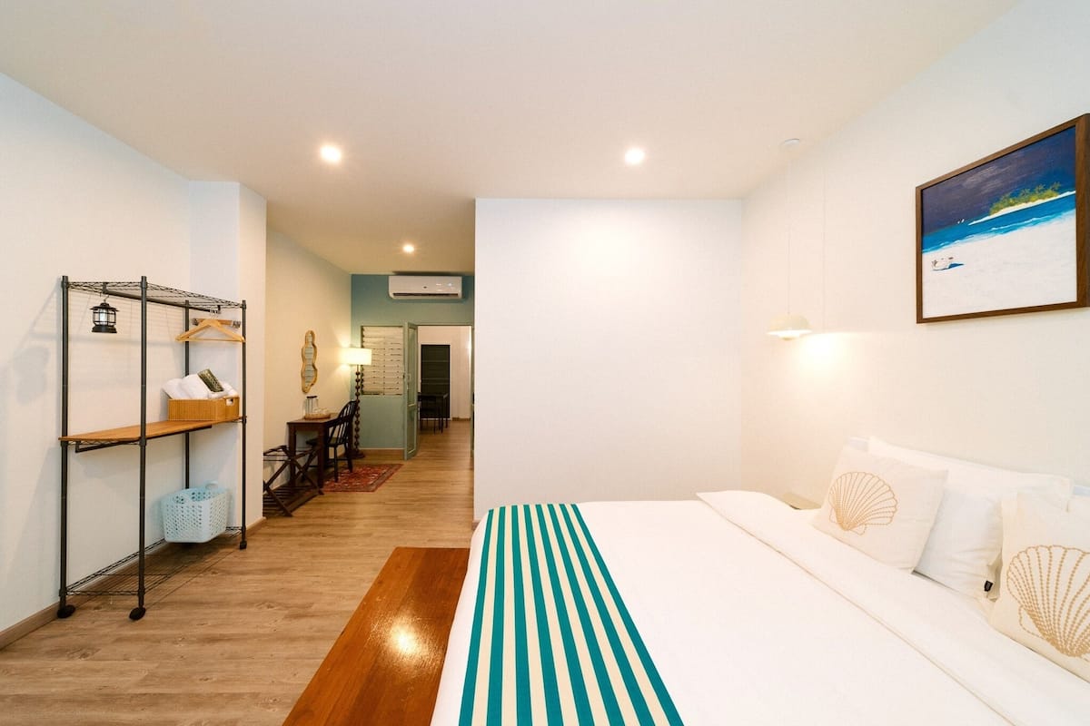 Habitación de hotel con cama, tendedero, escritorio y vista a la playa por la ventana.