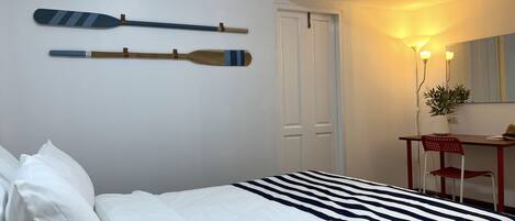 A bedroom with a bed, a desk, a chair, an air conditioning unit, and a door.