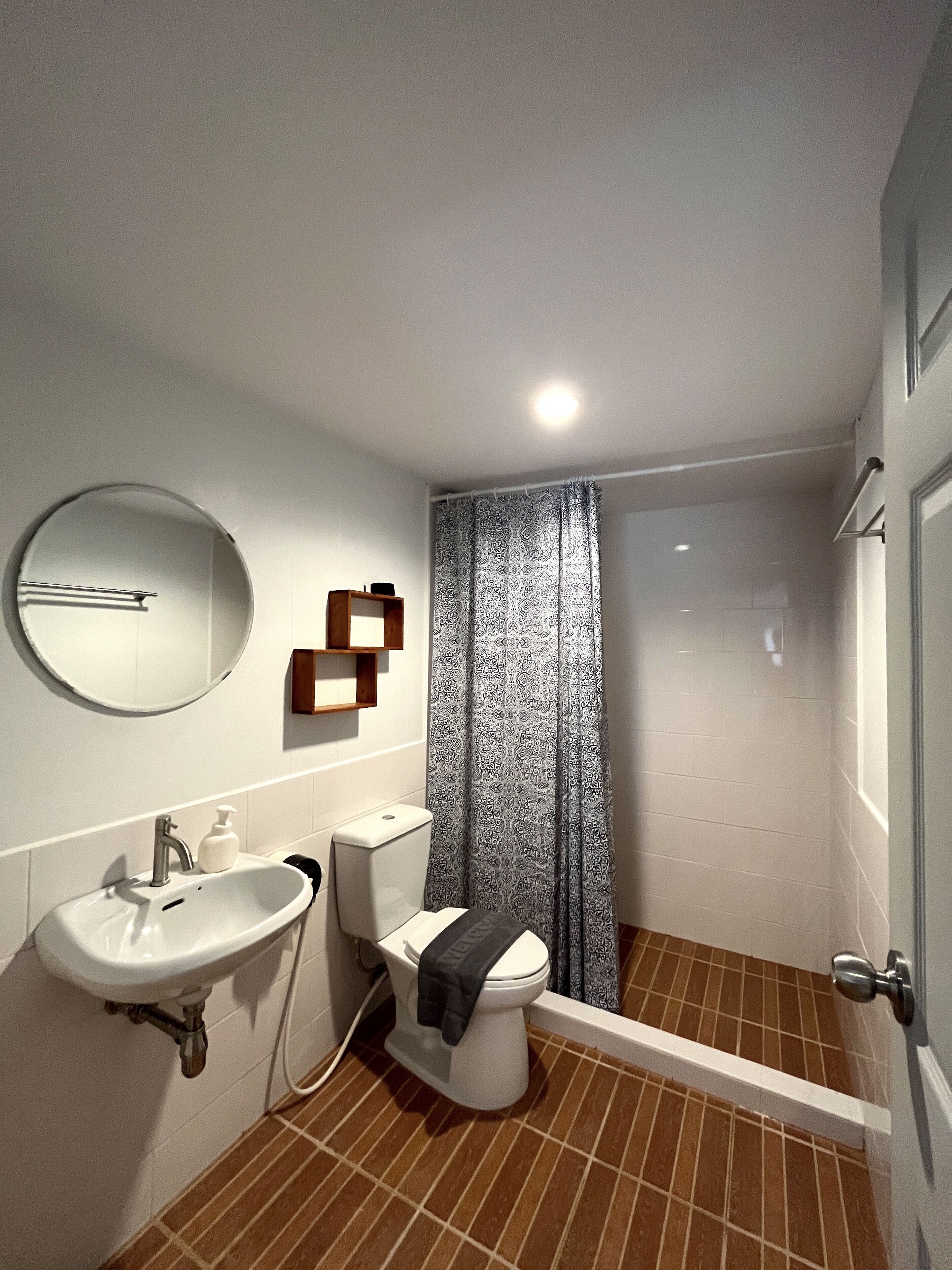 A modern bathroom with a white sink, toilet, and shower.