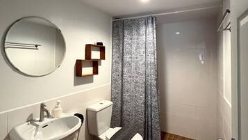 A modern bathroom with a white sink, toilet, and shower.