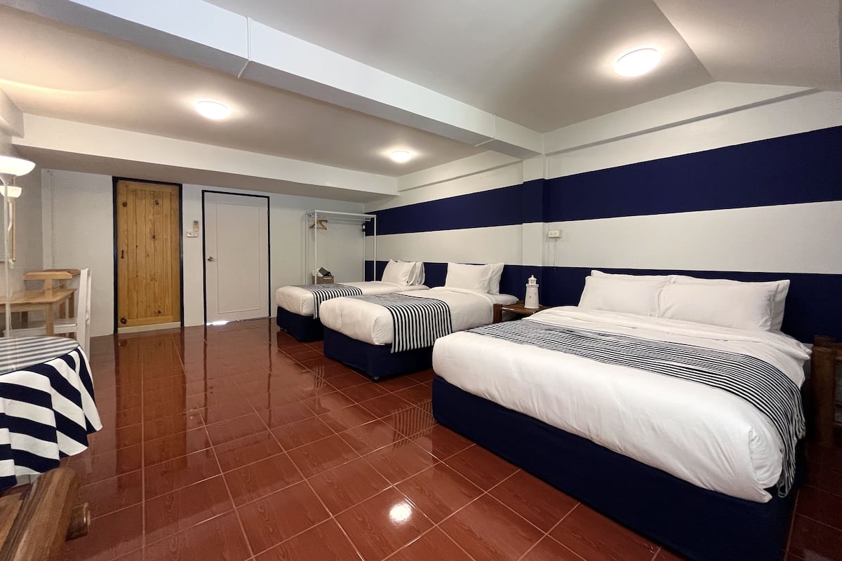 Habitación de hotel con dos camas, una puerta de madera, una mesita pequeña y una silla.