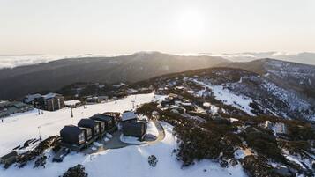 A snow-covered mountain resort with modern buildings, ski slopes, and a clear view of the surrounding peaks.