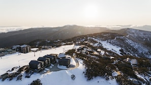 A snow-covered mountain resort with modern buildings, ski slopes, and a clear view of the surrounding peaks.