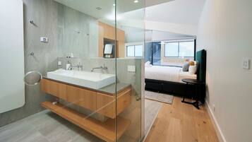A modern bathroom with a glass partition, a wooden vanity, and a large mirror.