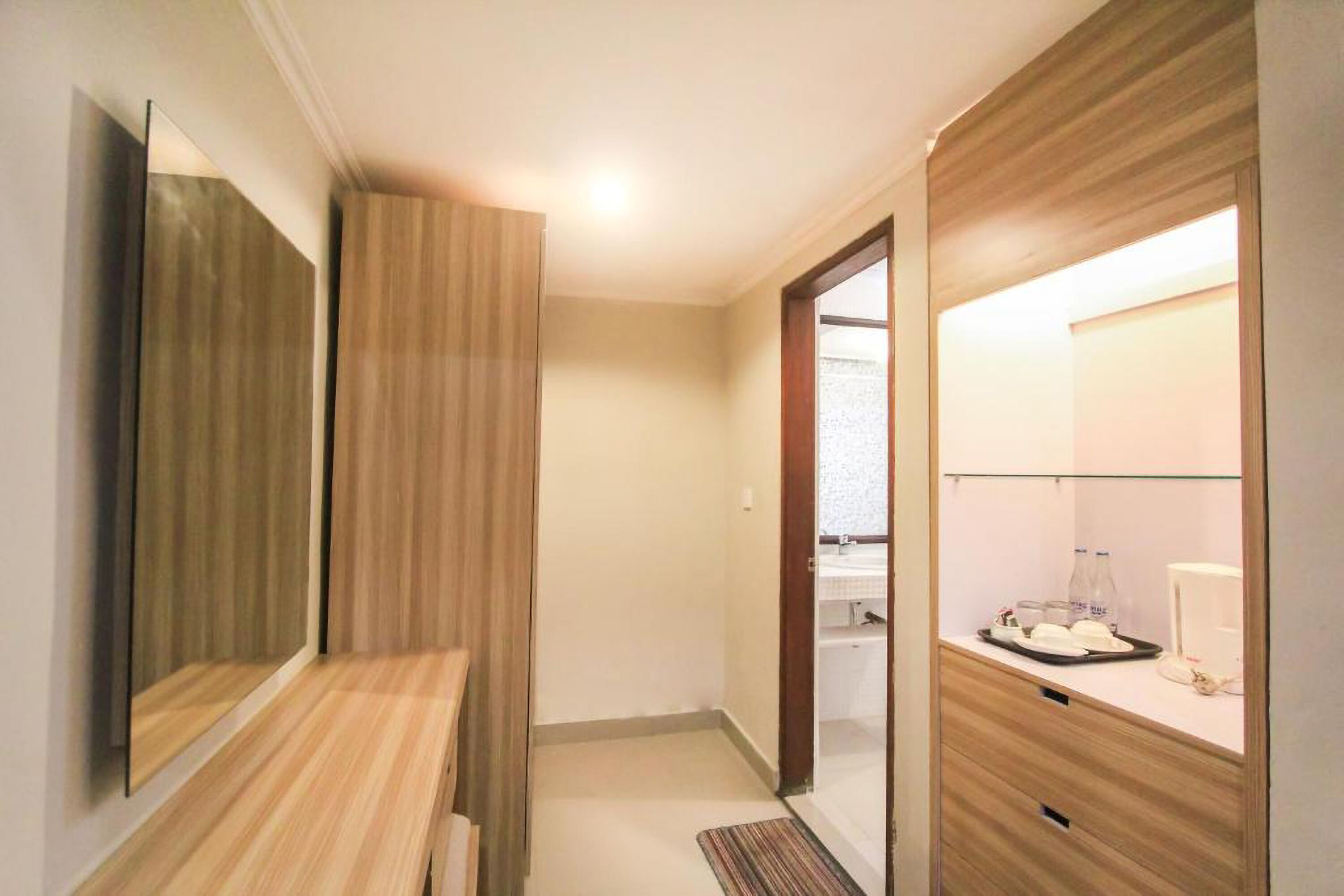 A modern hotel room with a wooden vanity, a mirror, a small table with toiletries, and a glass shower enclosure.