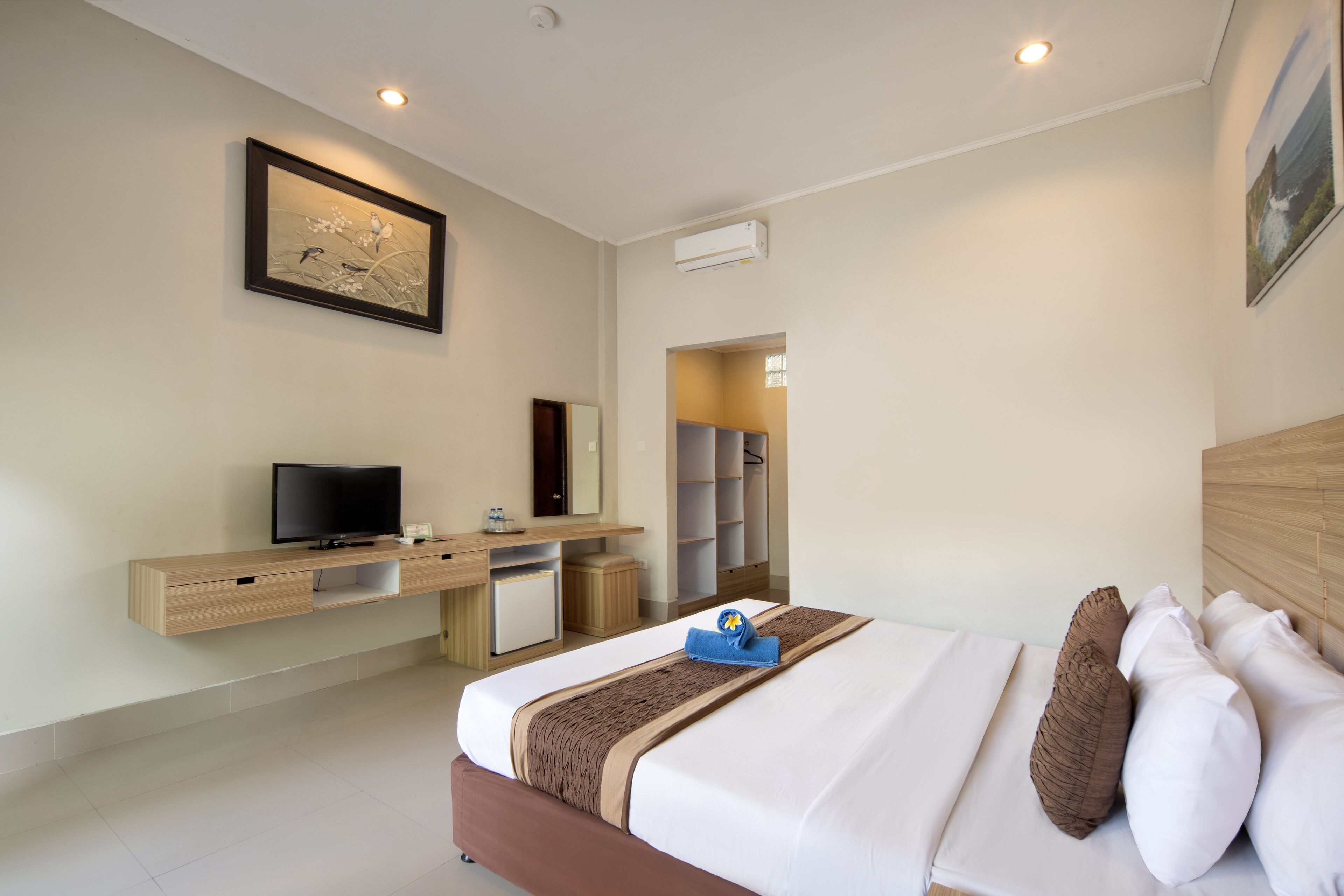 Quarto de hotel com uma cama, televisão, escrivaninha e guarda-roupa.