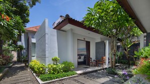 A modern house with a patio area, a small garden, and a door leading to a room with a bed and a chair. - Legian Village Beach Resort (Legian)