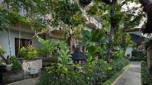 A garden pathway with potted plants and a thatched-roof structure. - Legian Village Beach Resort (Legian)
