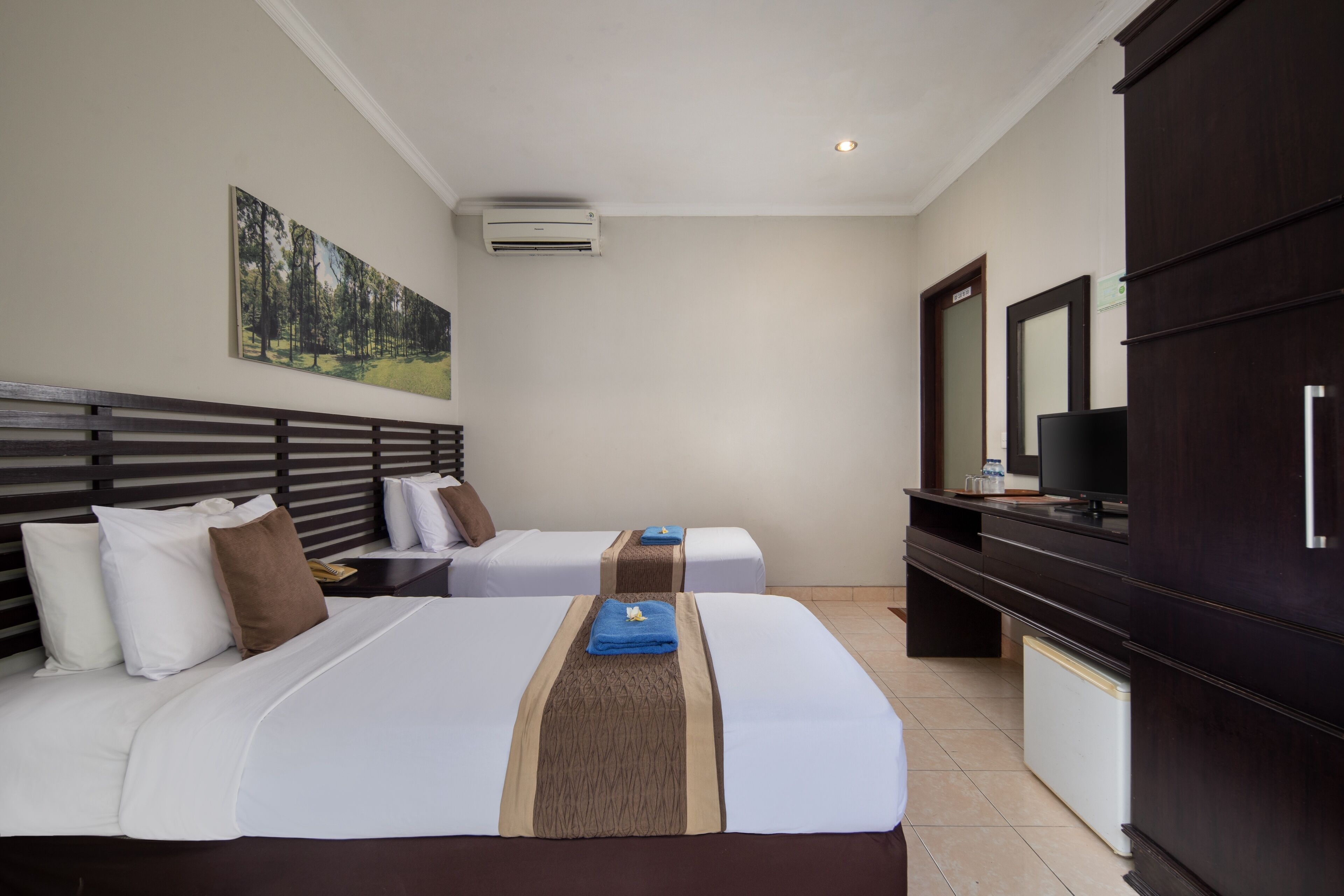 Habitación de hotel con dos camas, televisión, minibar y aire acondicionado.