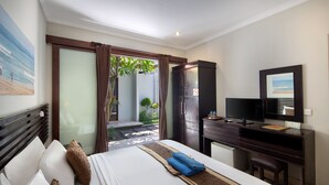 A hotel room with a bed, a desk with a computer, a television, and a view of the outdoors. - Legian Village Beach Resort (Legian)