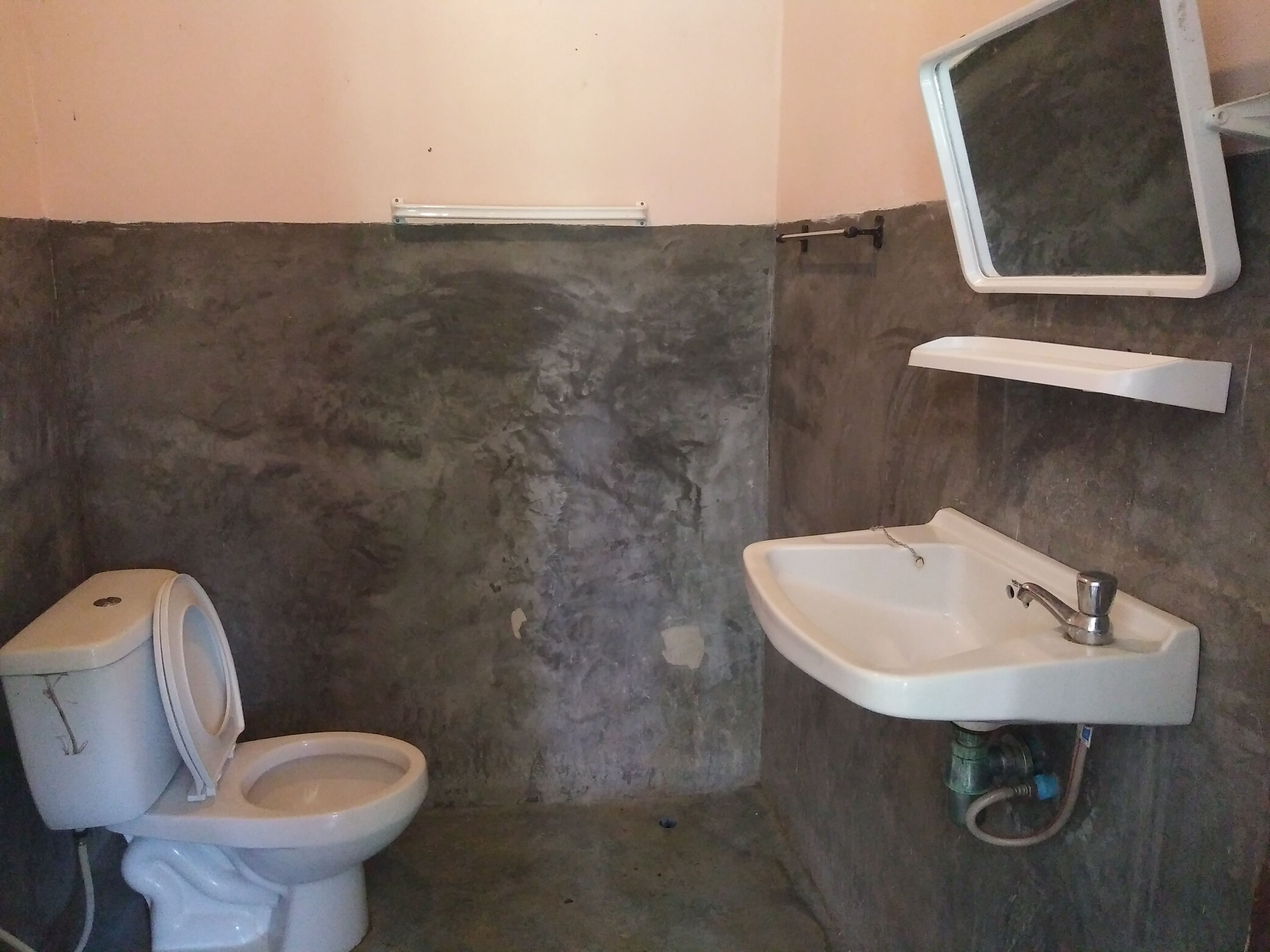 Un baño con inodoro, lavamanos y espejo.