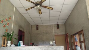 A reception area with a ceiling fan, a reception desk labeled "RECEPTION," and a potted plant. - Pai Park Cottage (Pai)