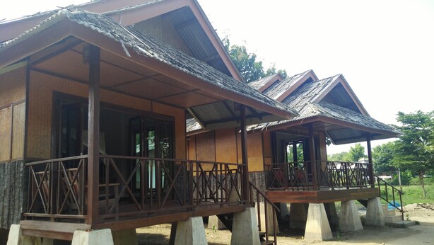 A series of elevated wooden structures with balconies, supported by concrete stilts, in a natural setting. - Pai Park Cottage (Pai)