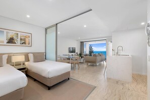 A hotel room with two beds, a desk, a sofa, a TV, and a view of the sea. - Breeze Mooloolaba (Mooloolaba)