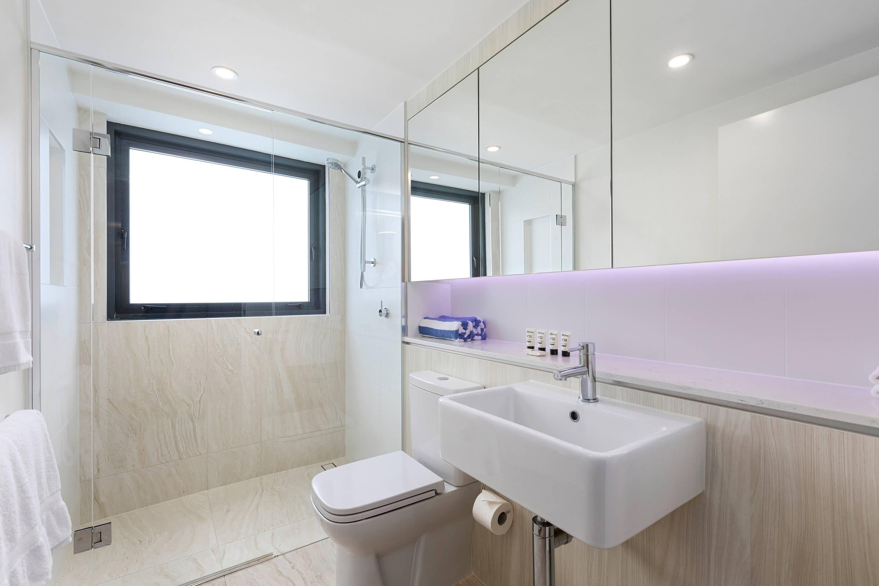 Een moderne badkamer met toilet, wastafel en douchecabine met glazen wanden.