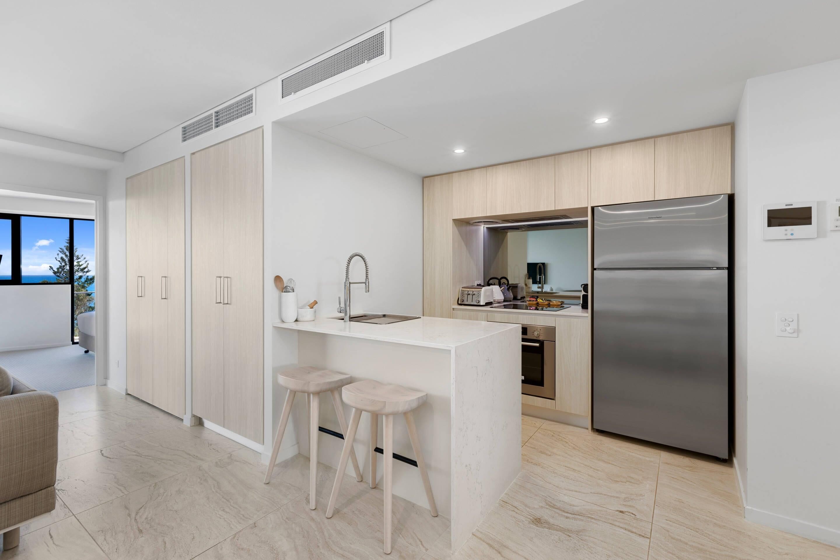 A modern kitchen with a central island, stainless steel appliances, and a view of the outdoors.