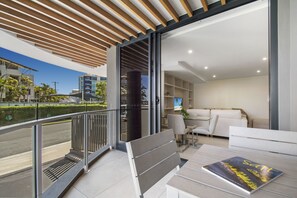 A modern apartment with a balcony, a sofa, a dining table, and a bookshelf.