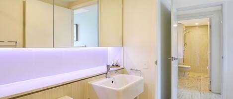 Een moderne badkamer met een wit wastafelmeubel, spiegel en toilet.