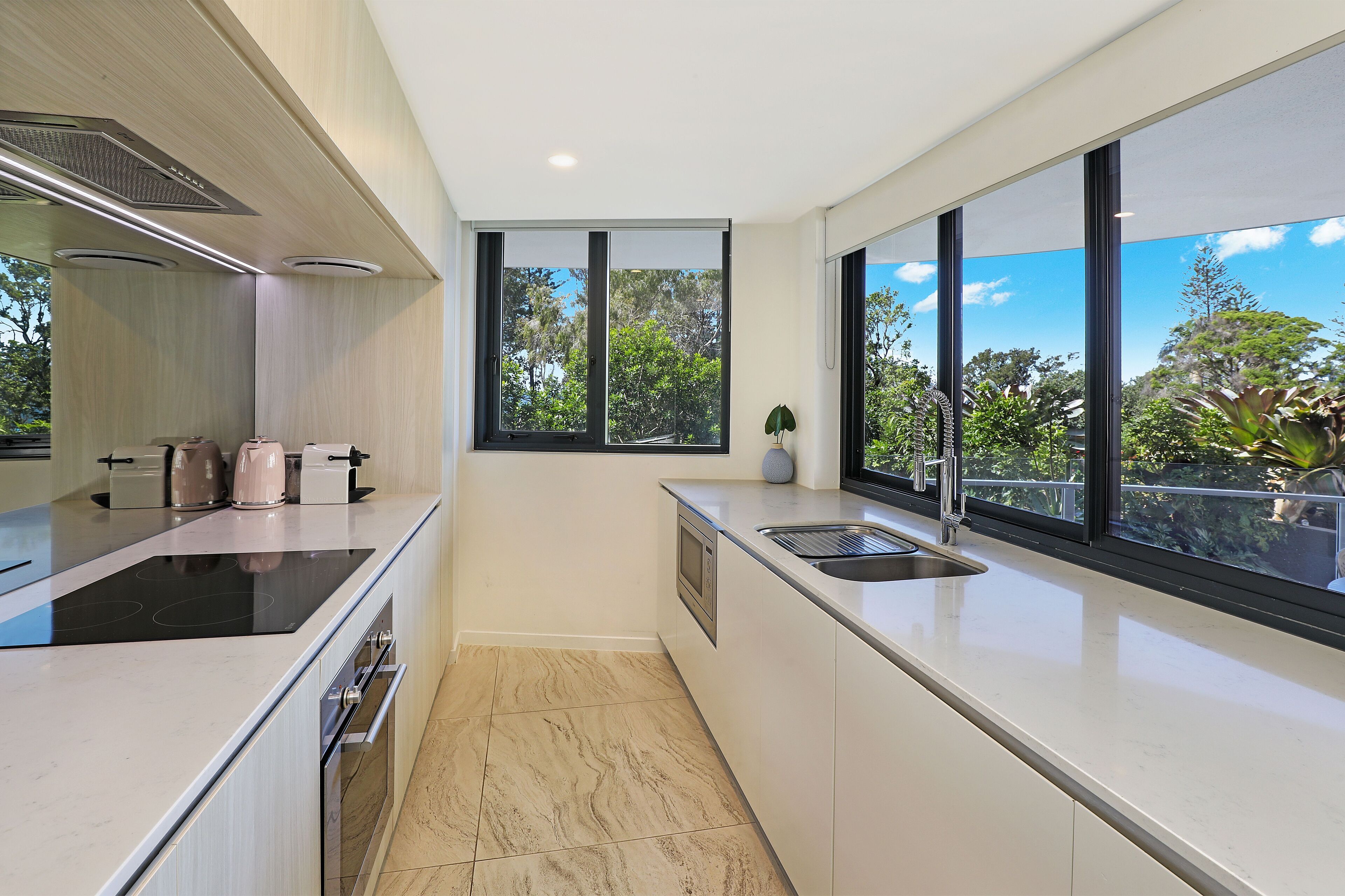 A modern kitchen with a large window, a built-in oven, and a sleek countertop.