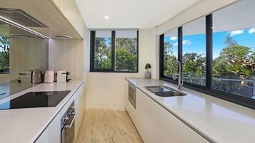 A modern kitchen with a large window, a built-in oven, and a sleek countertop.
