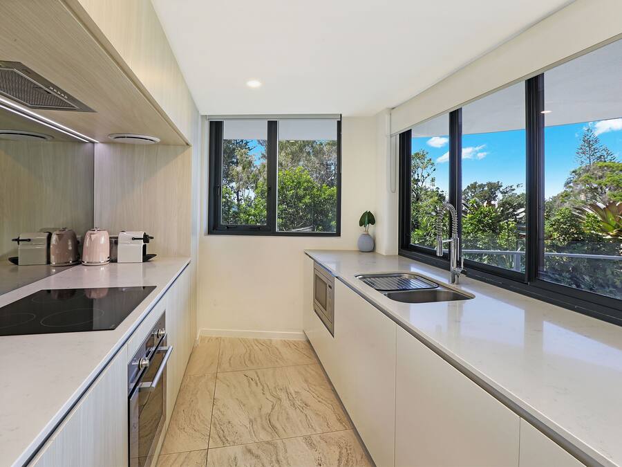 A modern kitchen with a large window, a built-in oven, and a sleek countertop.