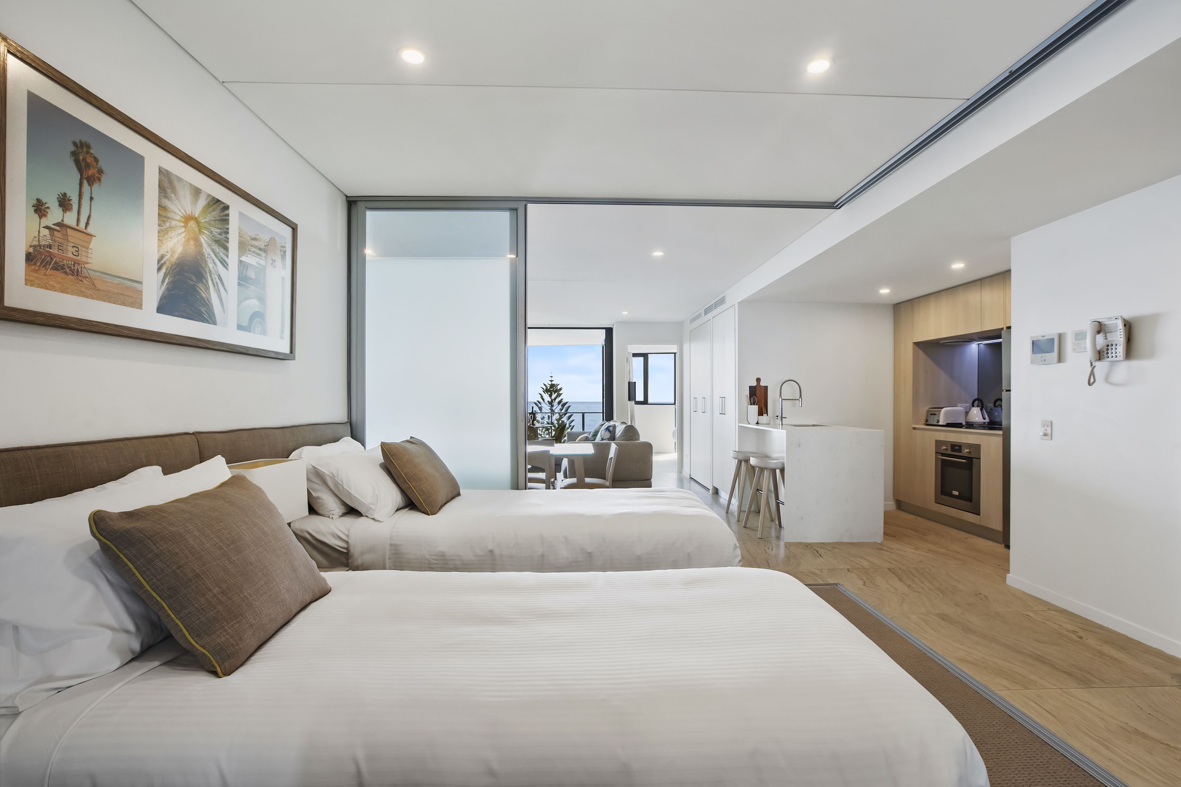 Et moderne hotelværelse med to senge, et spiseområde og et køkken.