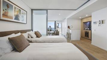 Et moderne hotelværelse med to senge, et spiseområde og et køkken.
