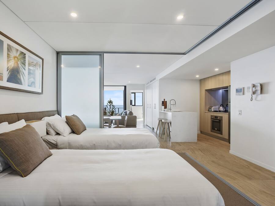 Et moderne hotelværelse med to senge, et spiseområde og et køkken.