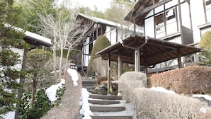 A traditional Japanese building with a wooden structure, stone steps, and snow-covered ground. - Kawaguchiko country cottage Ban (Fujikawaguchiko)
