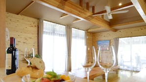 A wooden interior with a dining table, two wine glasses, a bottle of wine, and a bowl of fruit salad. - Kawaguchiko country cottage Ban (Fujikawaguchiko)