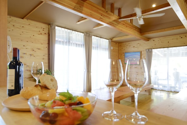 Un interior de madera con una mesa de comedor, dos copas de vino, una botella de vino y un bol de ensalada de frutas.