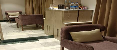 A hotel room with a seating area featuring two sofas and a cabinet with toiletries.