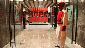 Et hotellobby med en receptionsdisk, en mand i traditionelt tøj, og en marmorgulv.