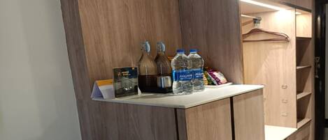 A wooden vanity with a mirror, two bottles of water, a bottle of juice, and a small bar area with a menu.