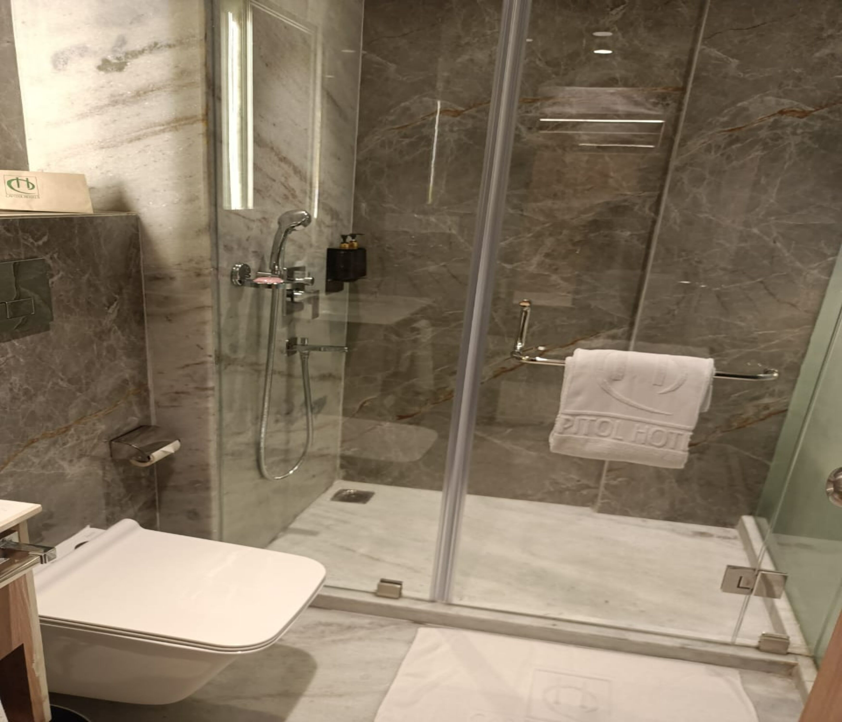 A modern bathroom with a glass-enclosed shower, marble walls, and a white sink.