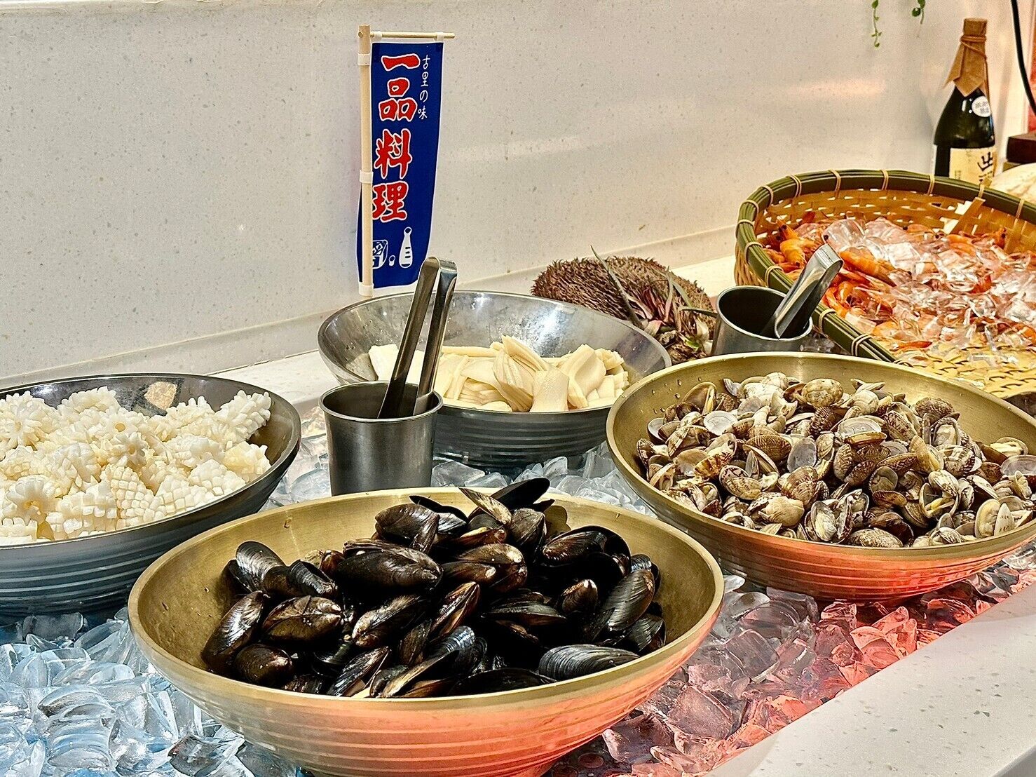 A seafood buffet with various dishes including mussels, clams, and shrimp, displayed on ice.