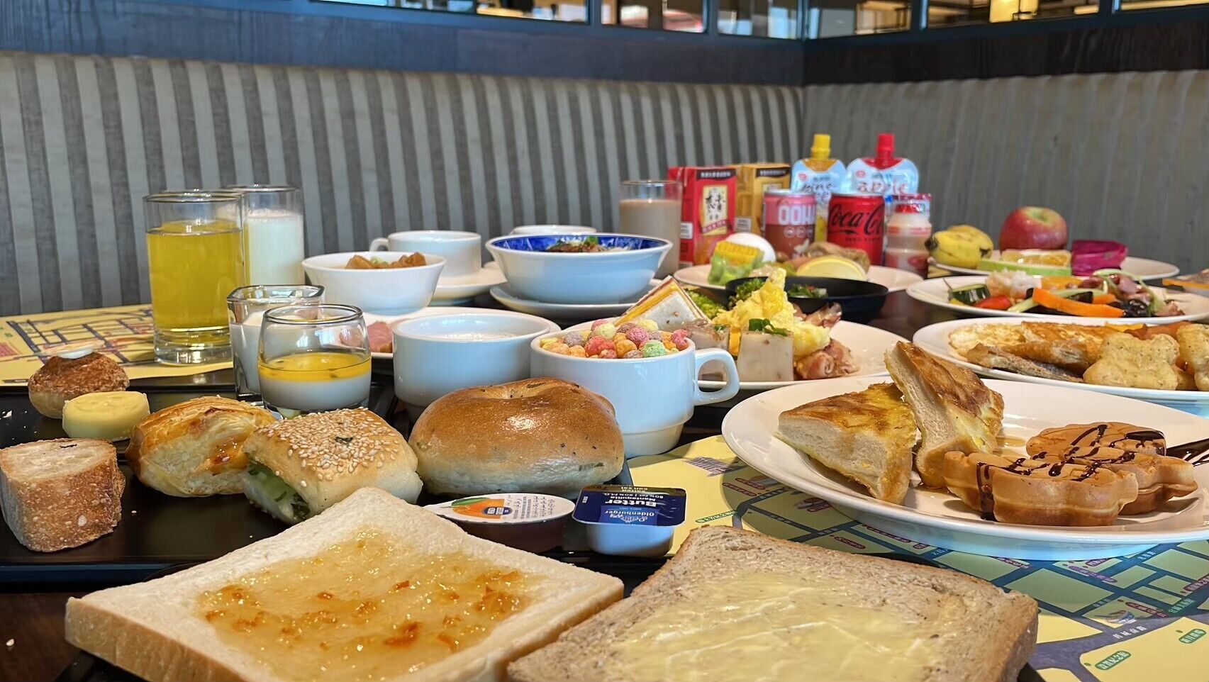 A breakfast buffet with various dishes, including bread, pastries, and beverages.