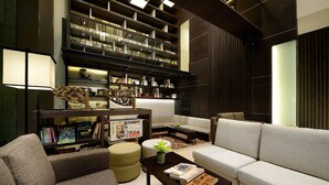 A modern living room with a sofa, armchair, and a bookshelf filled with books. - The Walden (Yilan)